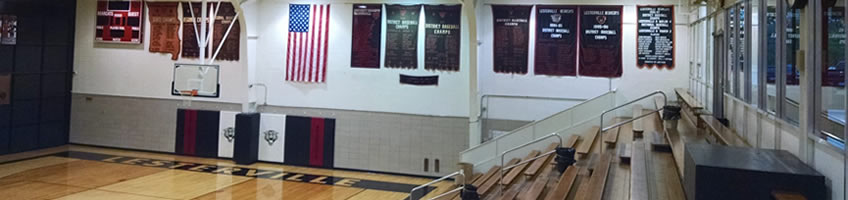 photo of the end of Lesterville Schools' gymnasium with a view of the scoreboard, basketball goal, banners, and bleachers